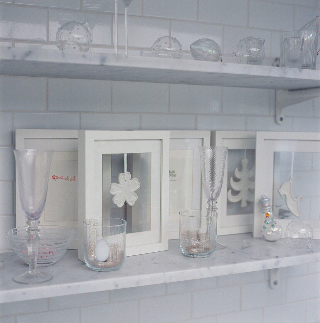 Display of white Christmas decorations and glassware on open marble shelves