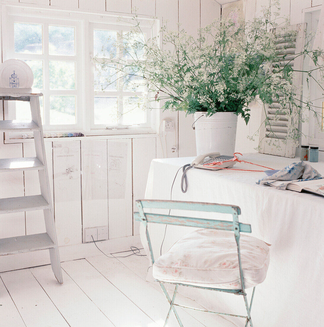 White washed panelled garden studio workshop with desk and linen table cloth
