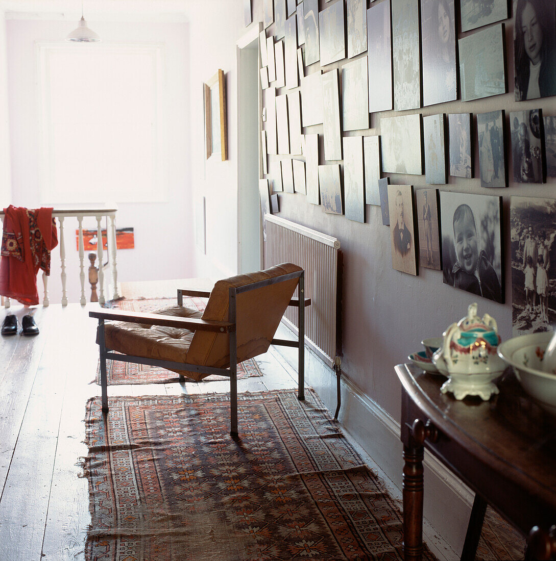 Ausstellung alter Familienfotos in Schwarz-Weiß und Sepia, aufgehängt an einer Wand in einem Flur im Obergeschoss, mit Sessel und Bodenteppichen
