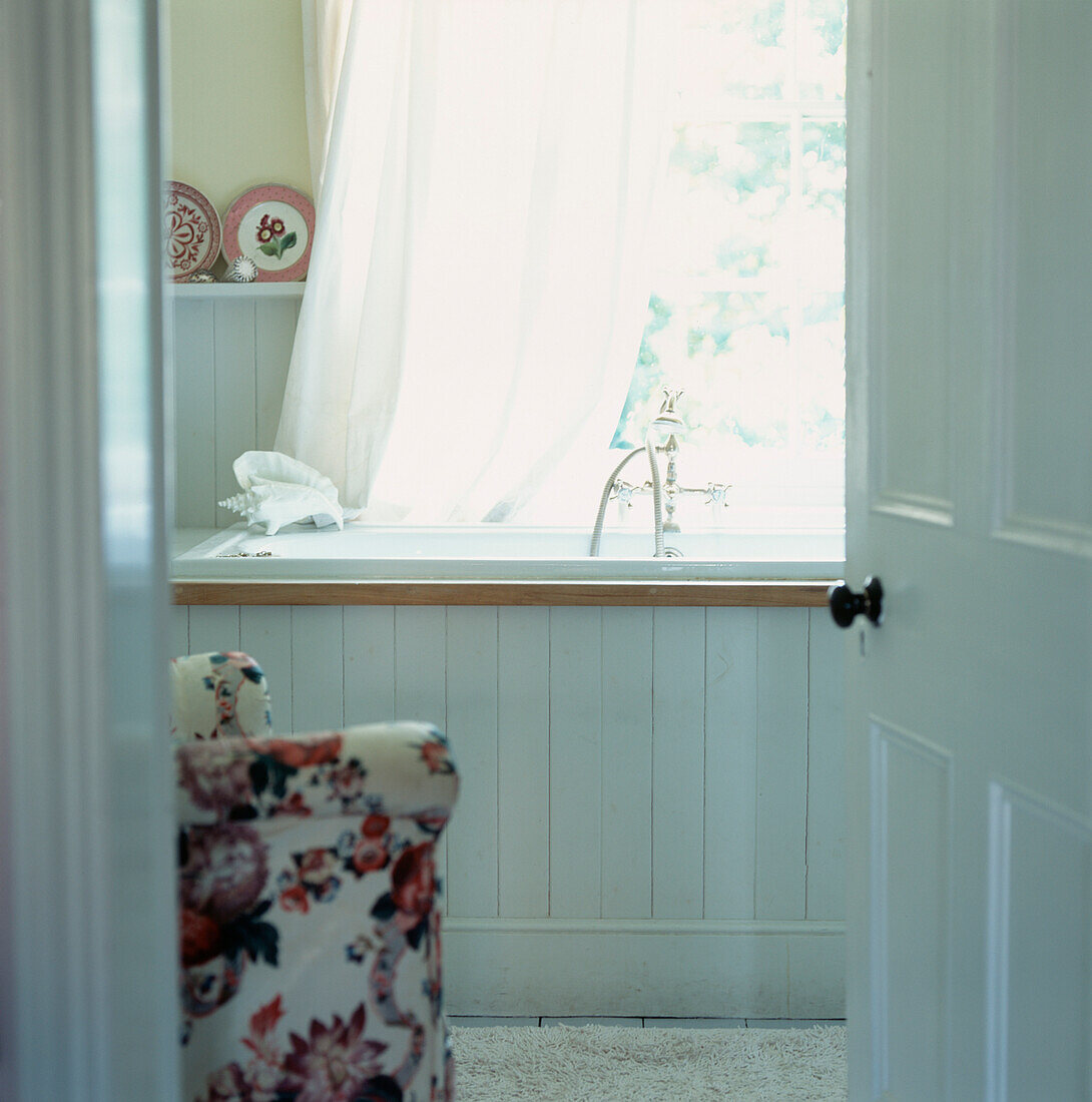 White paneled bathroom with large sash window bath and vintage taps