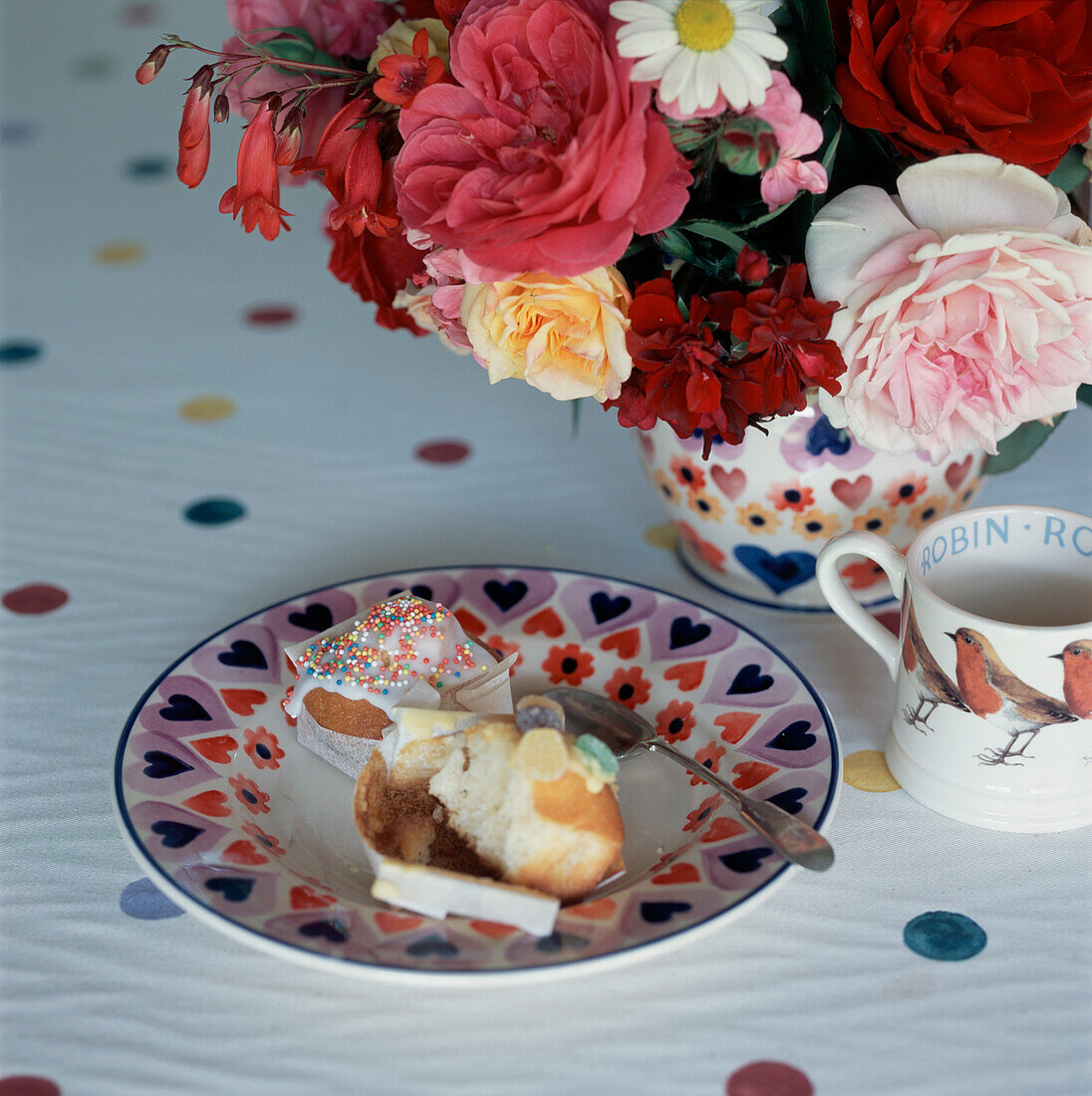 Gemustertes Geschirr mit Kuchen und Sommerblumen