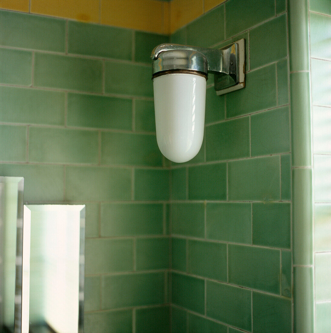 Art-Deco-Wandleuchte und grüne Badezimmerfliesen (Detailaufnahme)