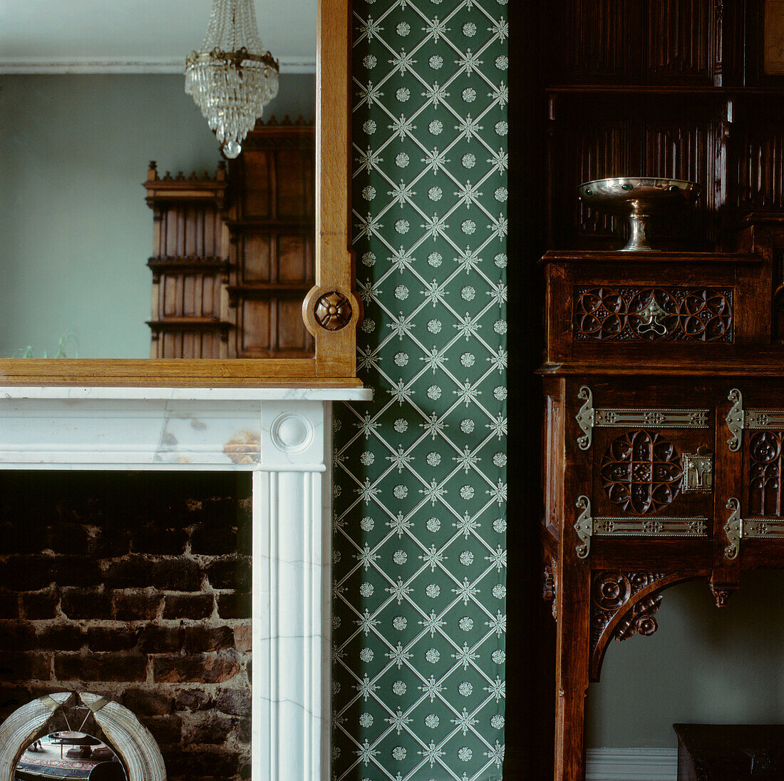 Detail of wallpapered chimney breast with fireplace and mirror