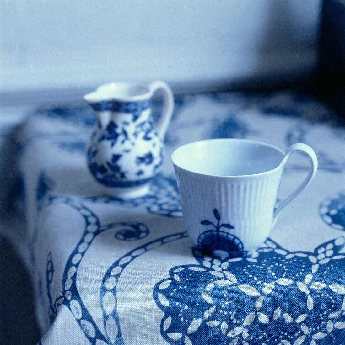 Detail einer Tischplatte mit blau-weiß gemusterter Tischdecke und Geschirr