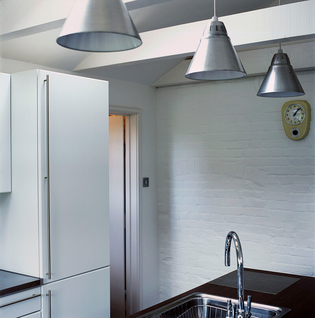 Minimalistische schwarz-weiße Balkenküche mit Hängelampen aus rostfreiem Stahl und Küchenspüle sowie gestrichenem Mauerwerk