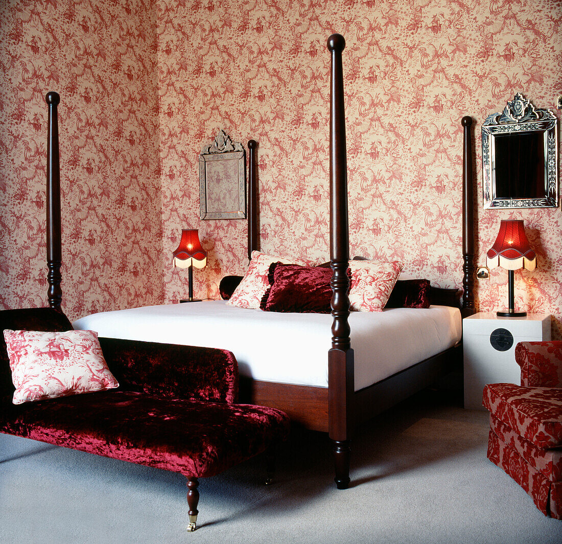 Rot-weiß gemusterte Tapete mit roten Dekomöbeln und Doppelbett in einem Schlafzimmer