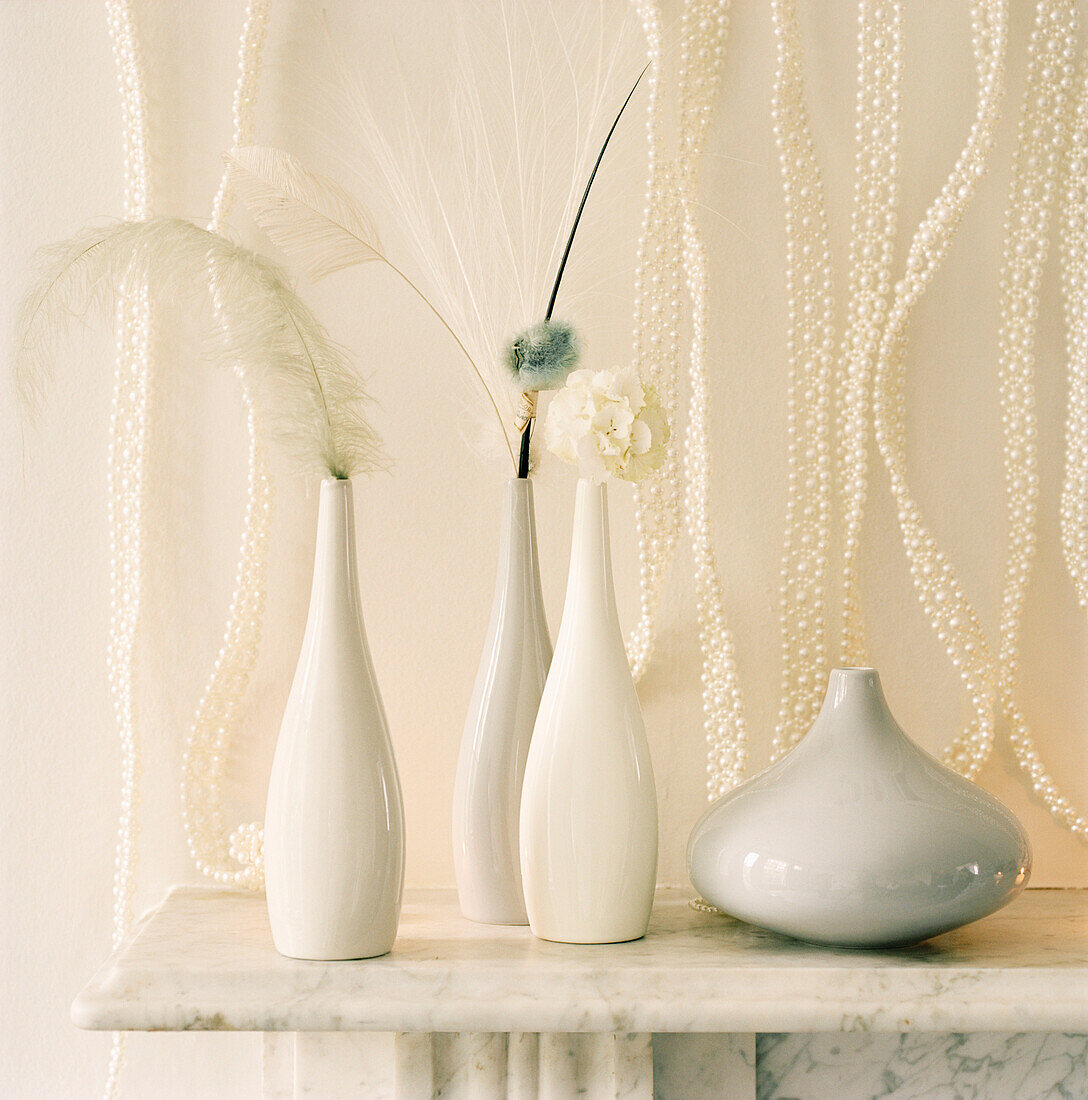 Detail von weißen Vasen und Weihnachtsdekorationen auf einem Marmorkaminsims