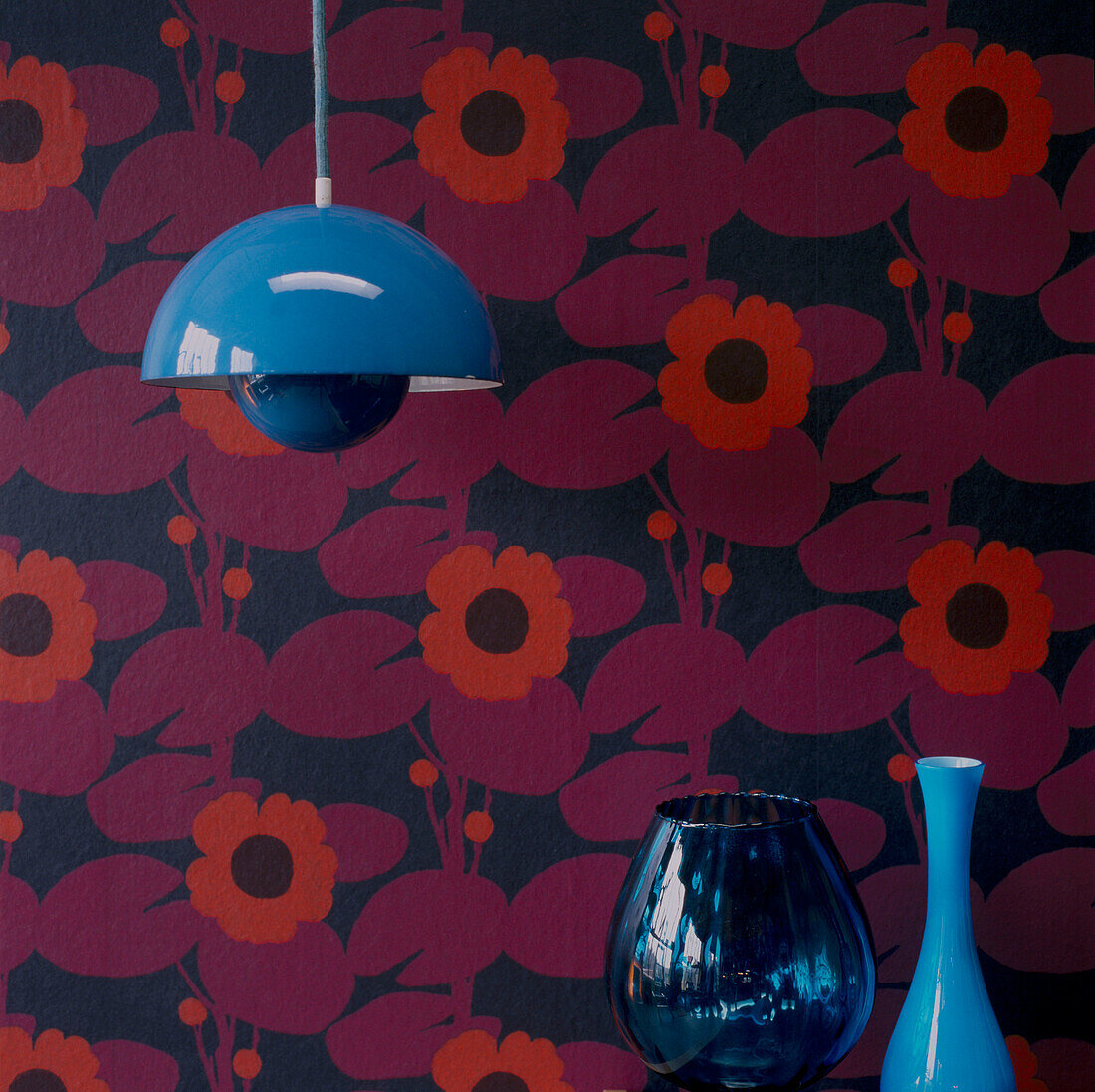 Red patterned wallpaper hanging light and glass home wares
