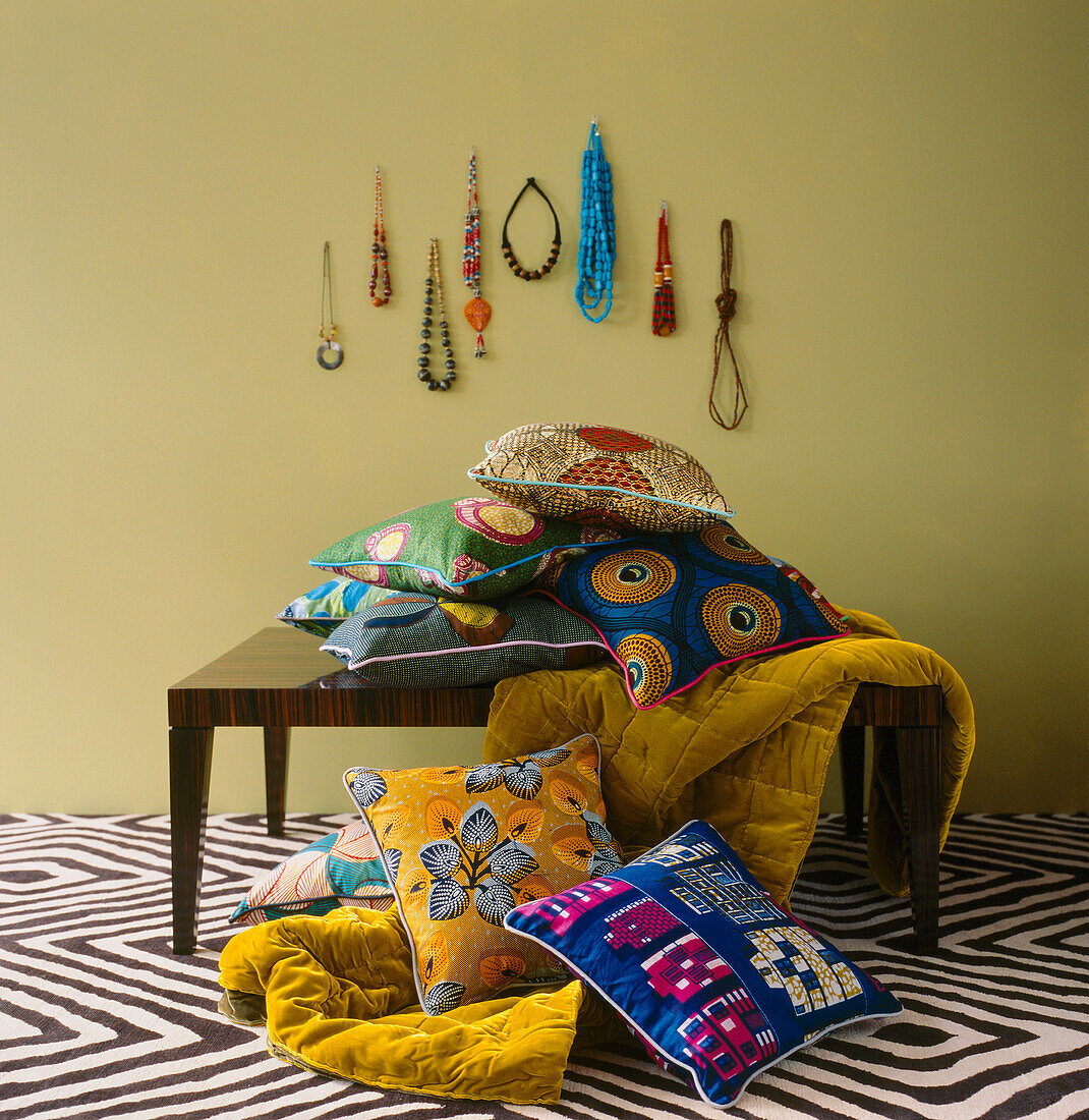 Gemusterter Stoff und Kissen auf einer Tischplatte mit gemustertem Teppich und einer Ausstellung von Halsketten