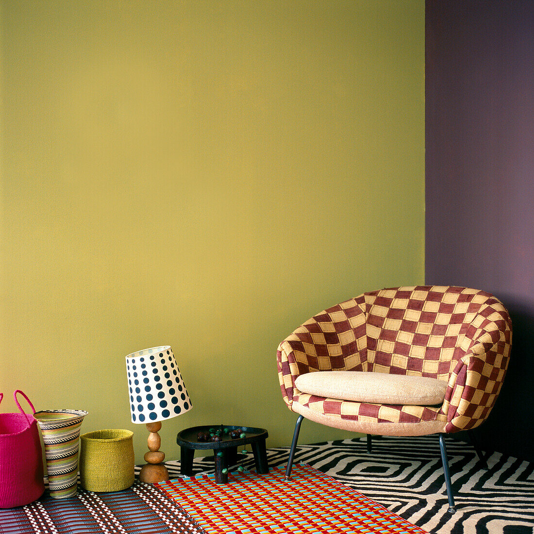 Wohnzimmer mit kariertem Sessel, gestrichenen Wänden, gemustertem Teppich, Teppichen und bunten Haushaltswaren
