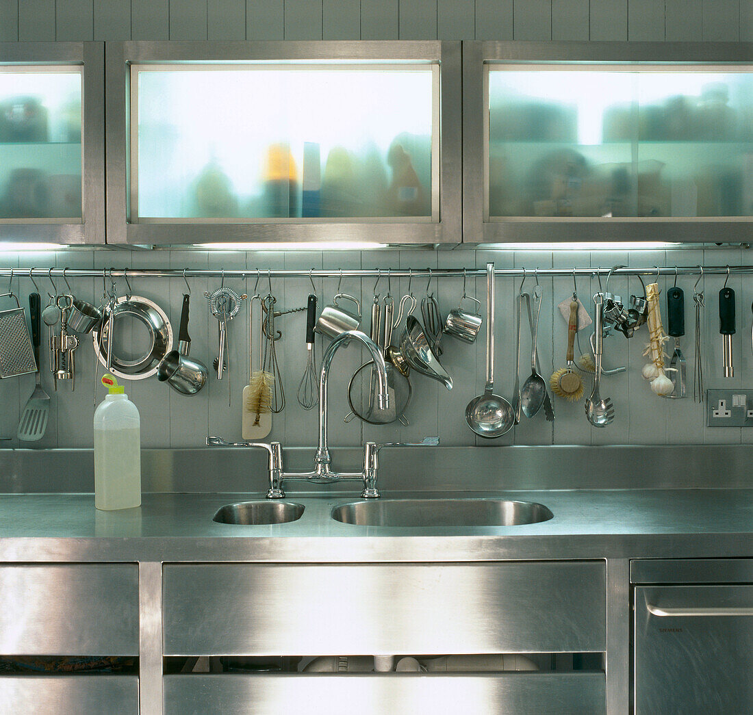Edelstahl-Einbauküche mit Spüle und Arbeitsplatten mit offener Auslage für Geschirr und Kochutensilien mit Milchglasfronten