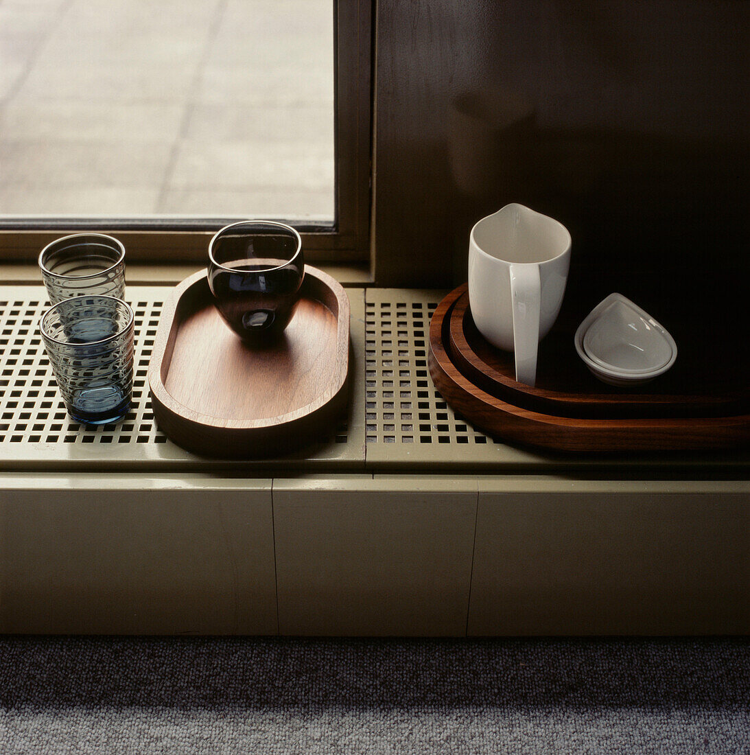 Display of contemporary homeware on wooden trays on a ventilated window sill