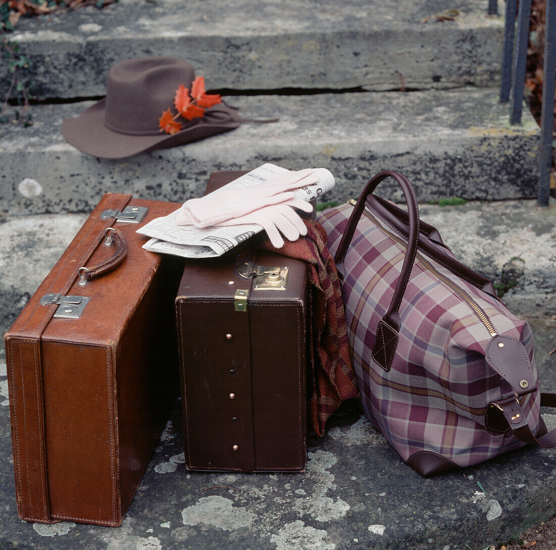 Two brown leather suitcases a holdall and a hat on the front doorstep