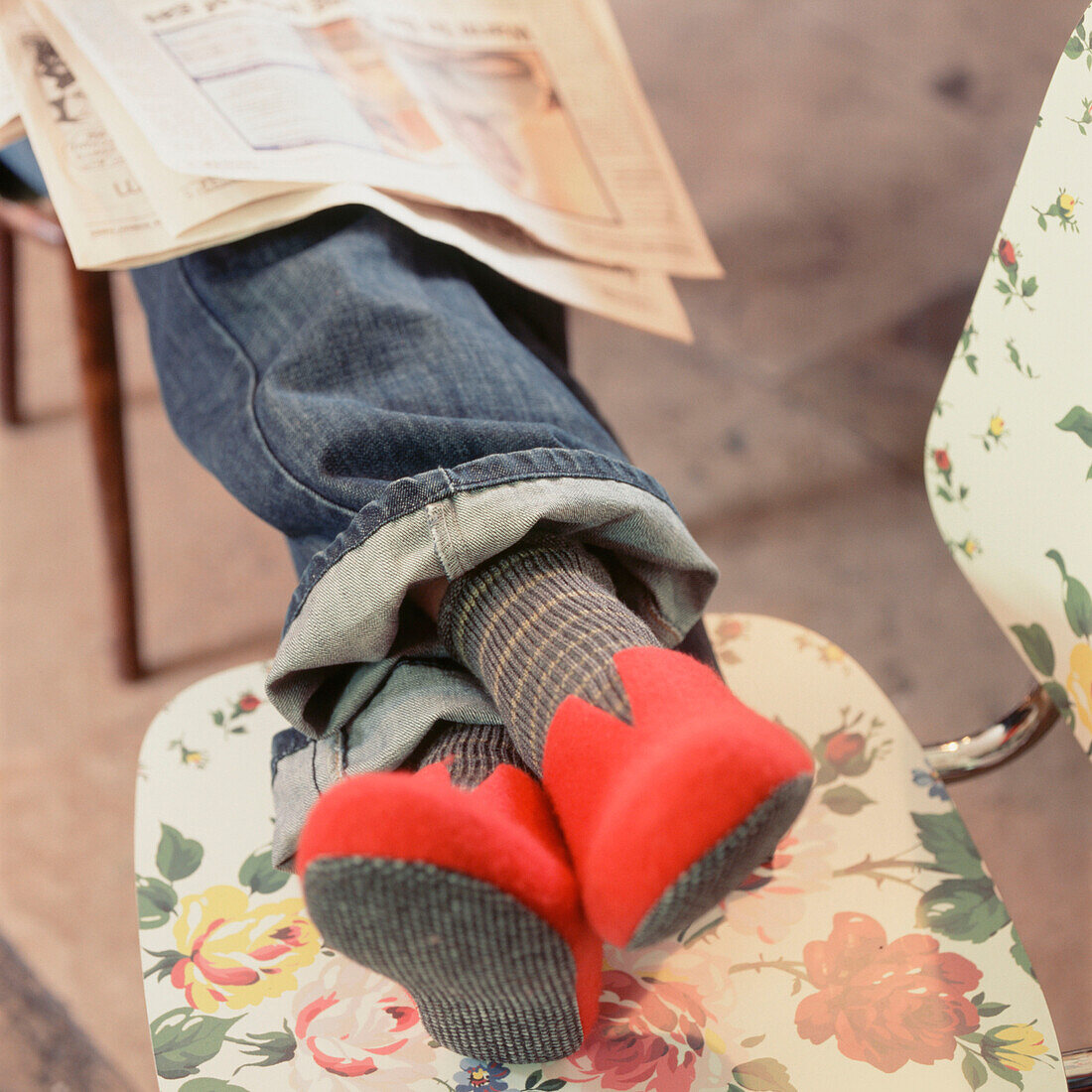 Person sitting with slippers on with legs up on a chair reading a newspaper
