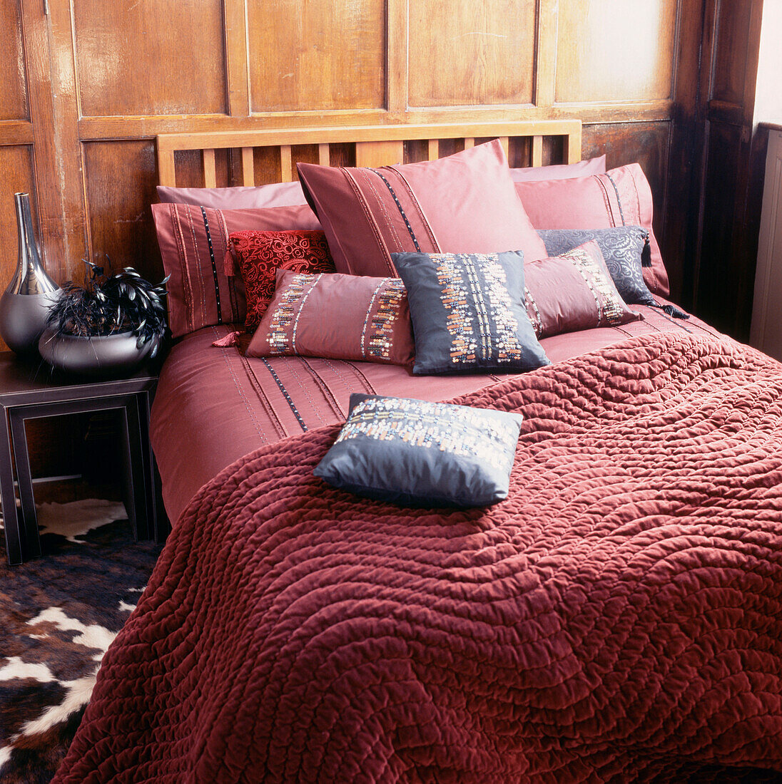 Doppelzimmer mit Holzpaneelen und einem Doppelbett mit buntem Bettzeug