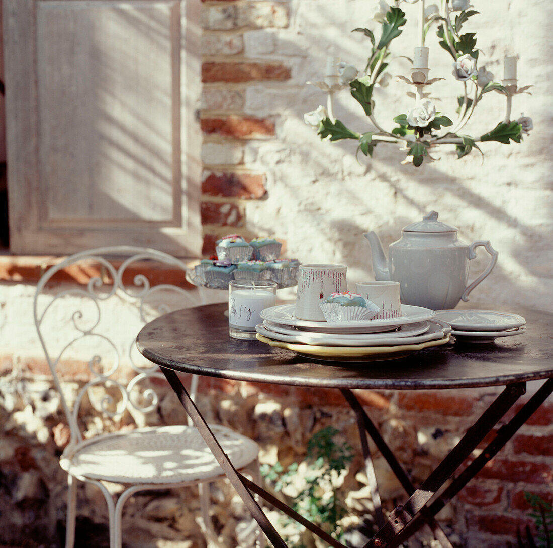 Gartenmöbel aus Metall mit gedecktem Tisch vor einem historischen Haus