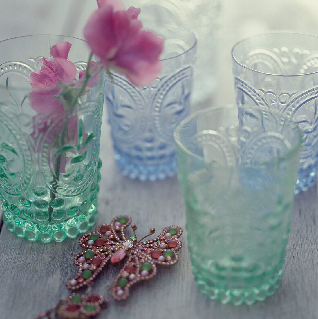 Vier grün und blau gefärbte Gläser auf einer hölzernen Tischplatte