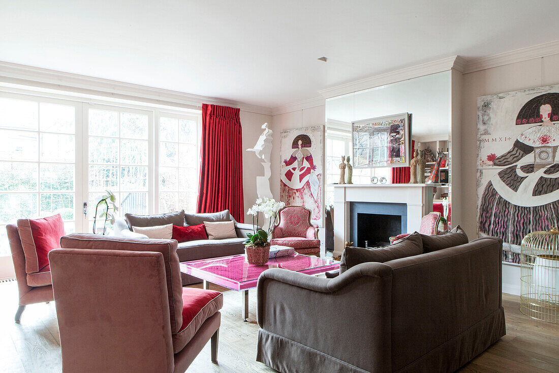 Living room with mirrored fireplace and red curtains at patio doors in contemporary London home England UK