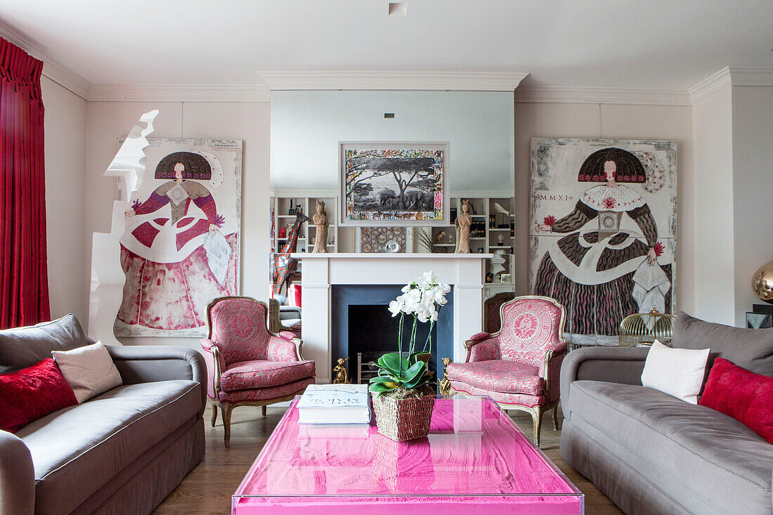 Passende Kunstwerke und Stühle mit verspiegelter Kaminbrüstung im modernen Wohnzimmer eines Londoner Hauses, England, UK