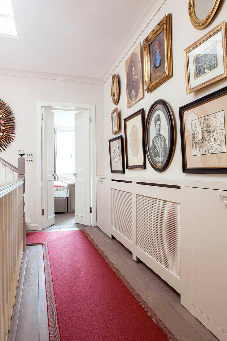 Kunstwerke im mit rotem Teppich ausgelegten Flur eines modernen Hauses in London England UK