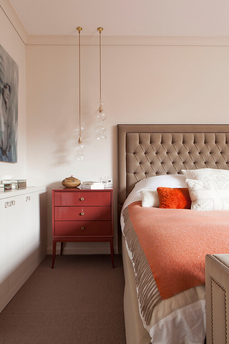 Geknöpftes Kopfteil mit pfirsichfarbener Decke in einem modernen Schlafzimmer in einem Haus in London, England UK