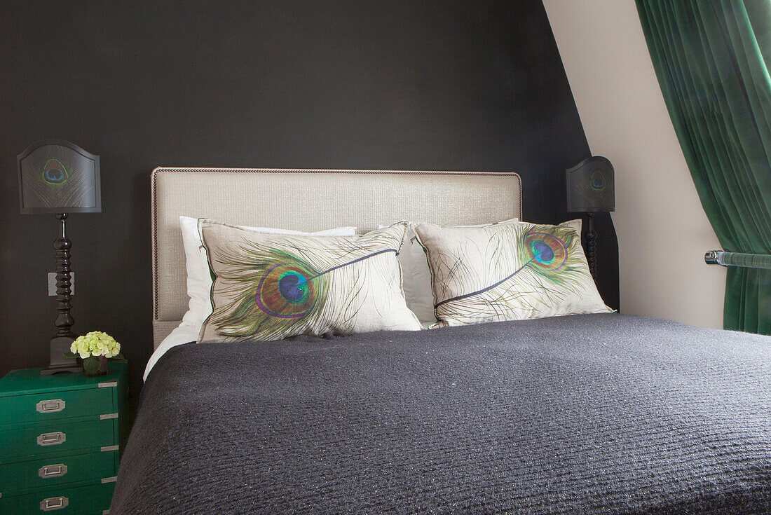 Pfauenfederkissen mit grünem Nachttisch in einem dunkelgrauen Schlafzimmer in einem modernen Londoner Haus England UK