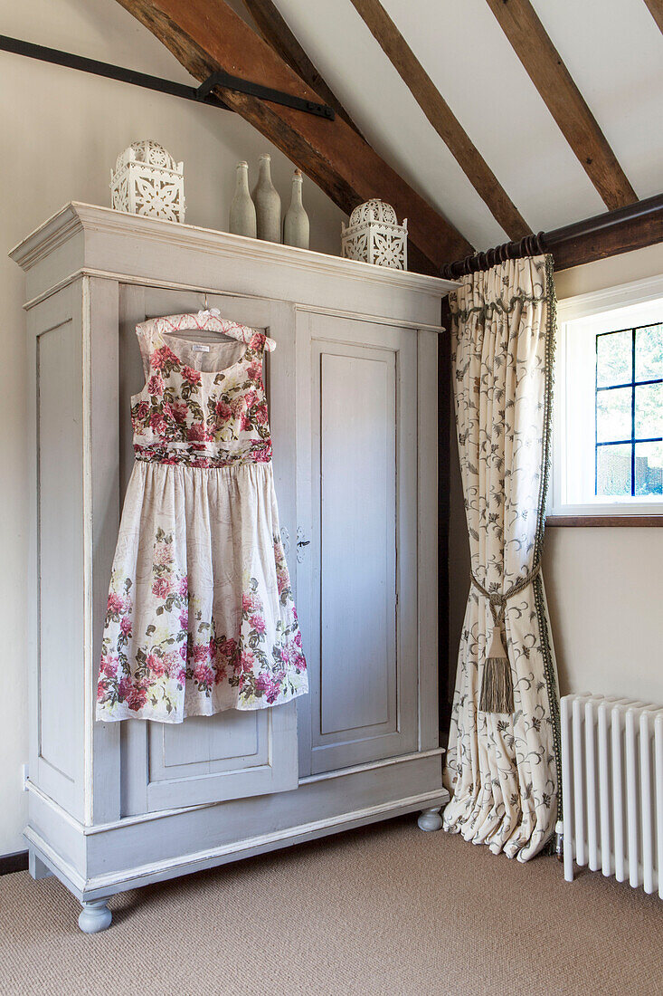 Sommerkleid hängt am Kleiderschrank am Schlafzimmerfenster in einer umgebauten Scheune in Surrey, England