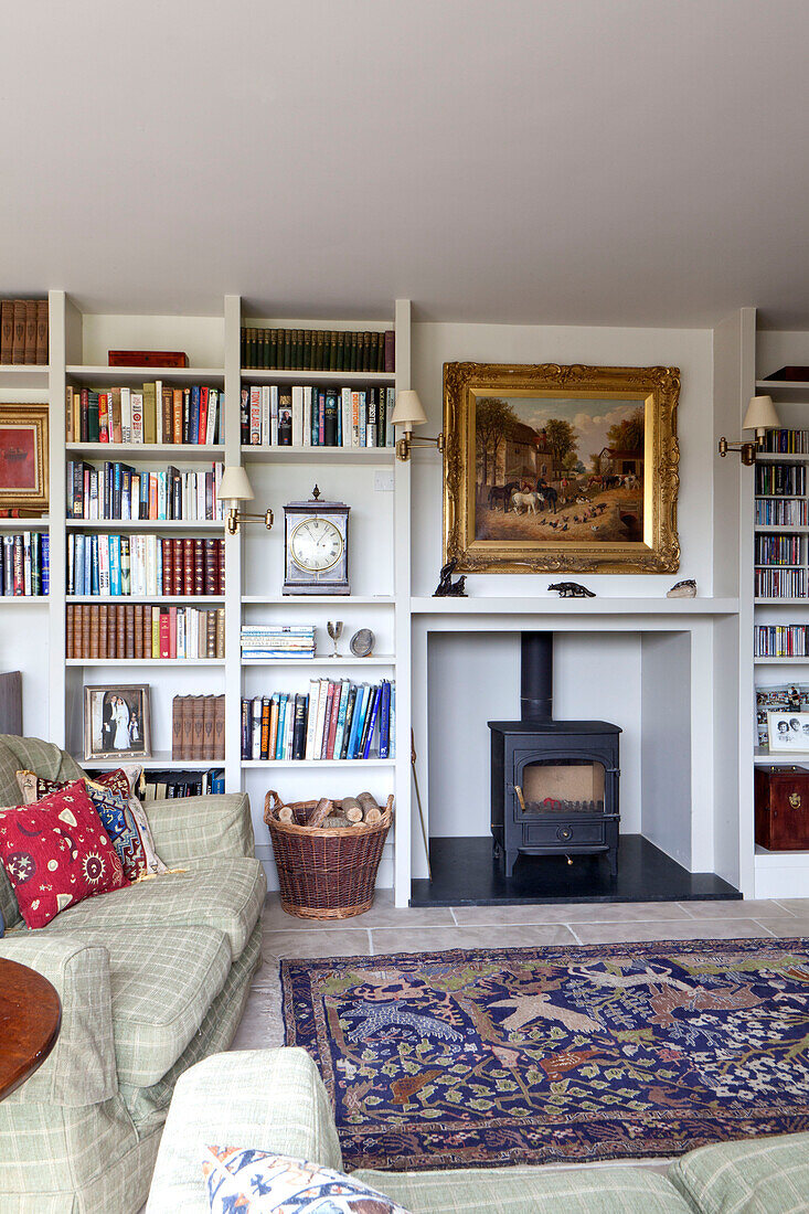 Bücherregale und Holzofen im Wohnzimmer eines Landhauses in Wiltshire England UK