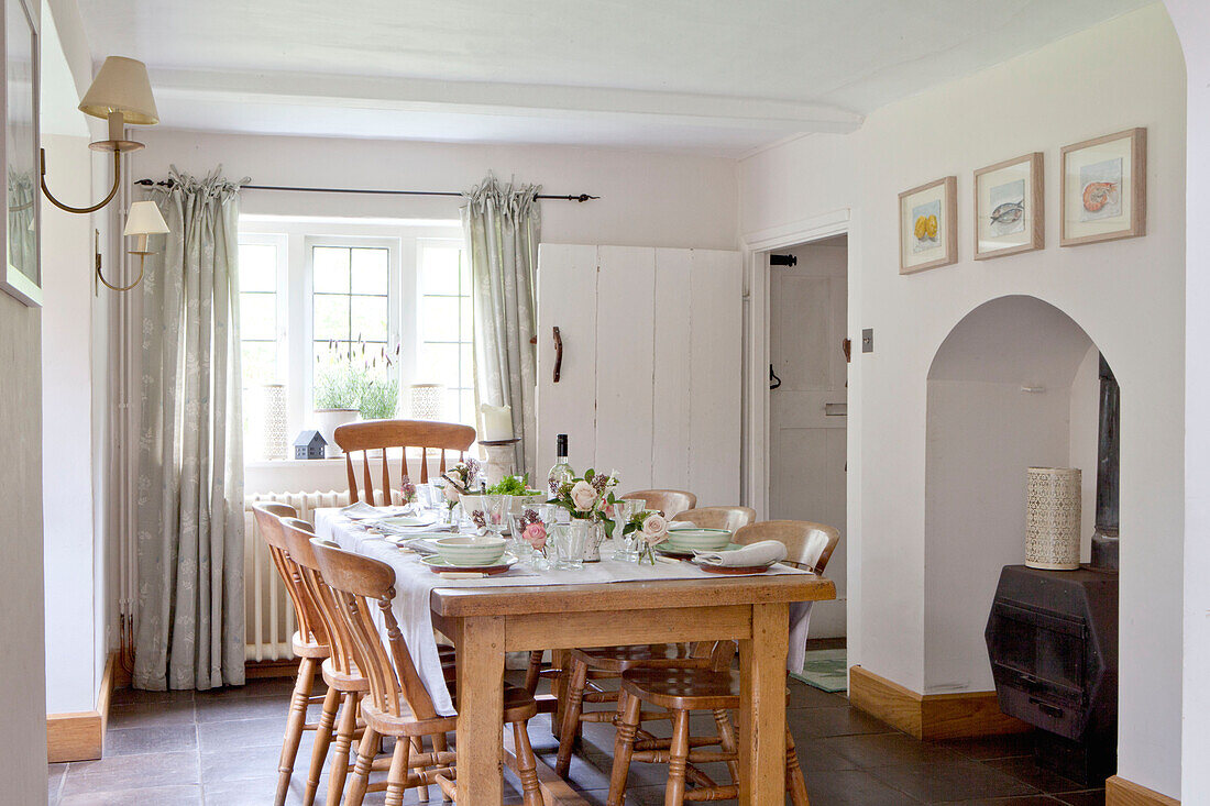 Wooden dining table and chairs with recessed woodburner in Surrey cottage England UK