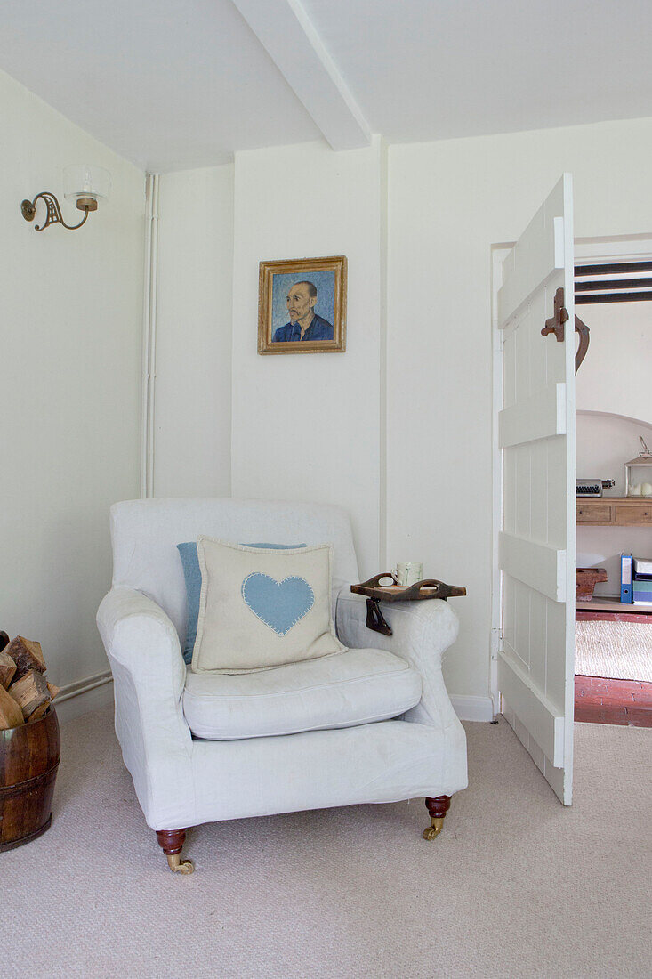 Sessel mit herzförmigem Kissen im Wohnzimmer eines Landhauses in Surrey, England