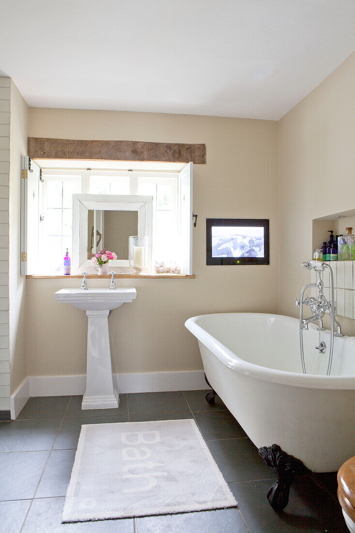 Freistehende Klauenfußbadewanne mit Sockelbecken im Badezimmer eines Landhauses in Surrey England UK