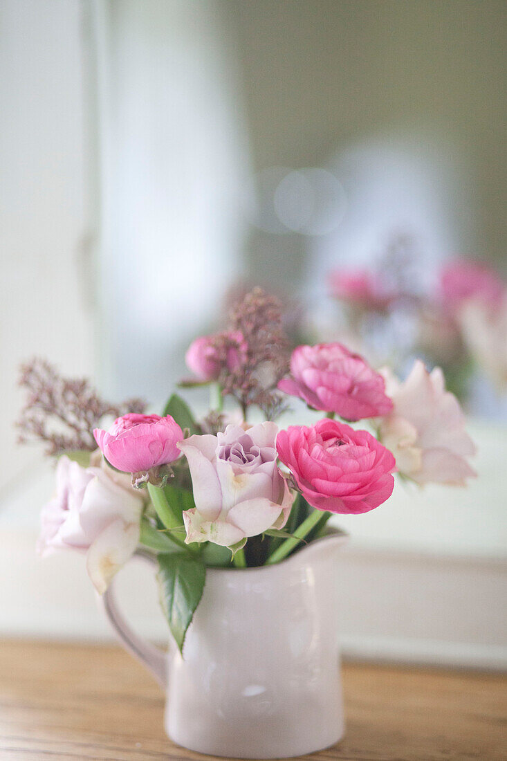 Pink roses in jug on shelf in Surrey cottage England UK