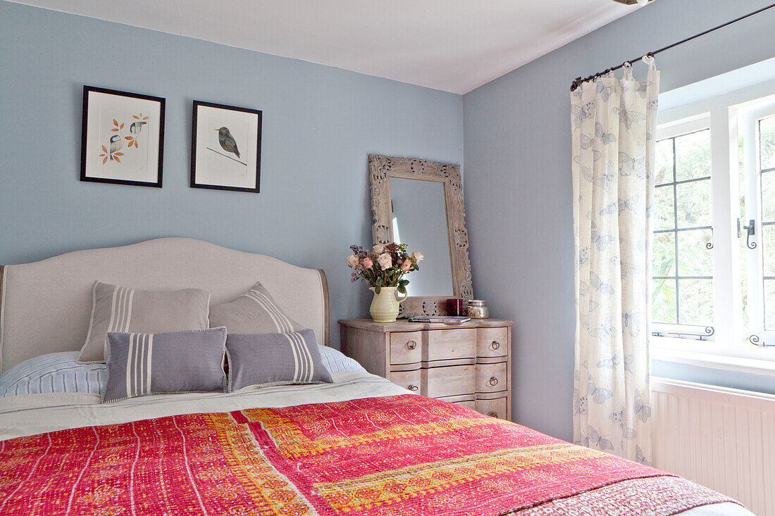 Rot bestickte Bettdecke im blauen Schlafzimmer eines Landhauses in Surrey England UK