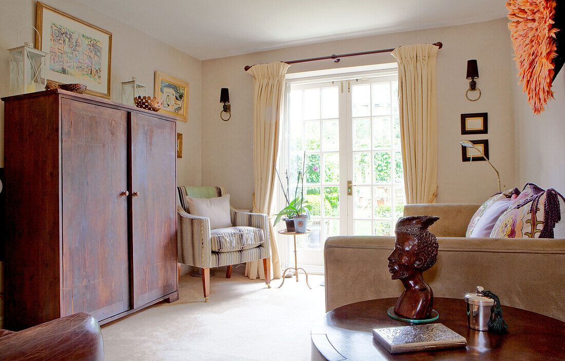 Holzschrank und Beistelltisch mit geschnitztem Holzkopf in einem modernen Haus in Chelsea, London UK