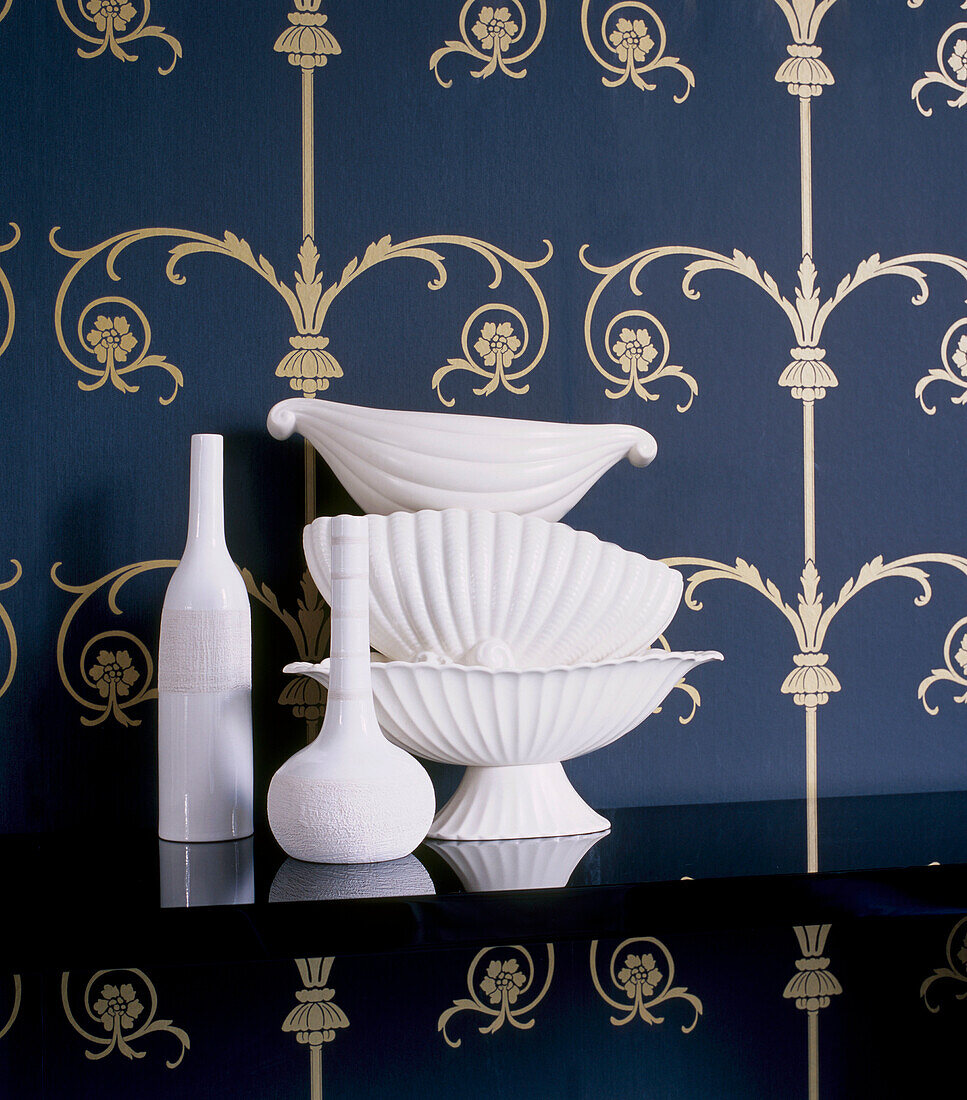 Blaue und goldene Mustertapete mit schwarzem Regal, auf dem weiße Keramikartikel ausgestellt sind