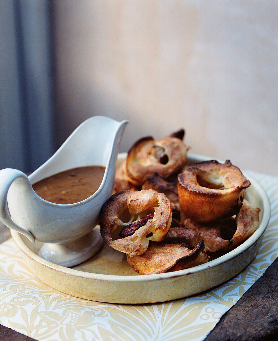 Dish full of Yorkshire puddings and a jug of gravy