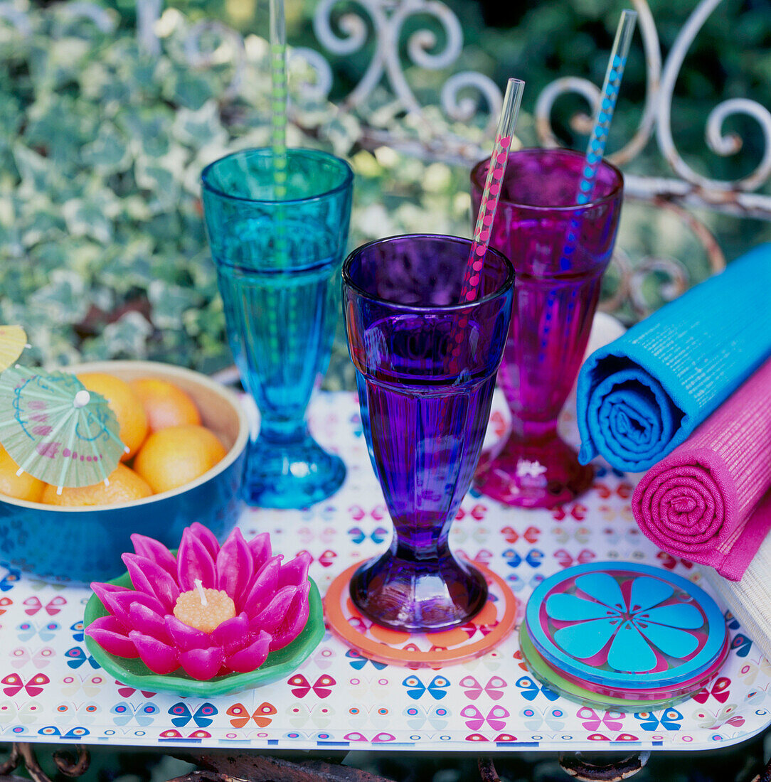 Coloured glassware and crockery on a table in the garden