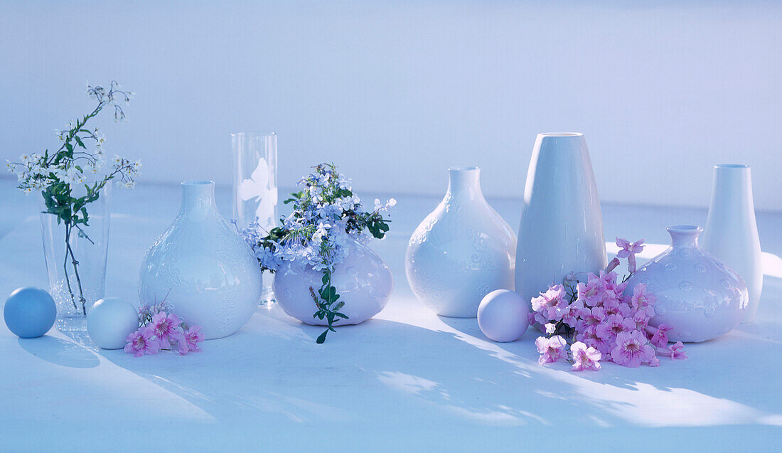 Stilleben mit Keramikvasen und Haushaltswaren auf einem Gartentisch mit Blumenauslage