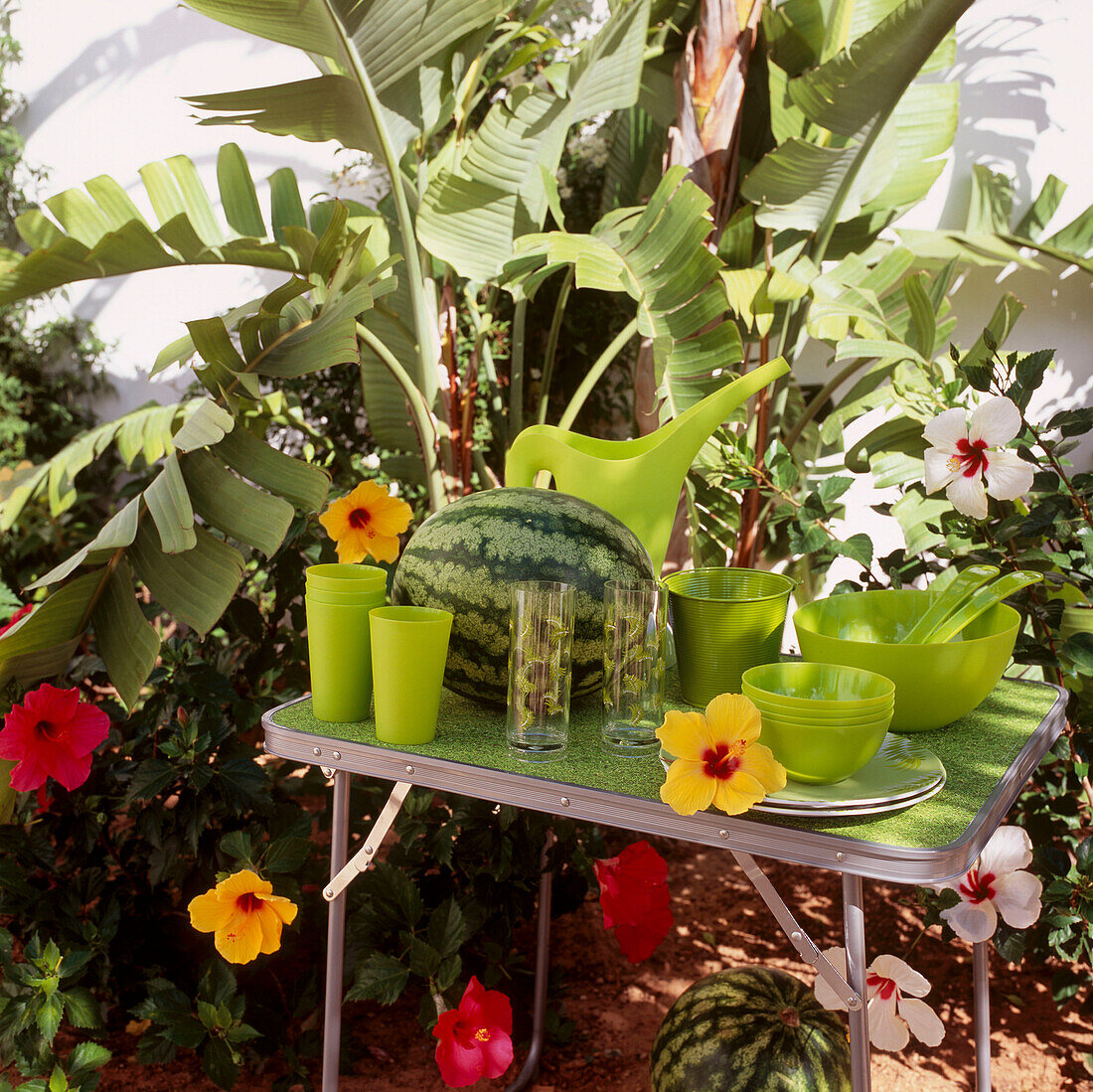 Green coloured plastic tableware on a foldaway table in a garden