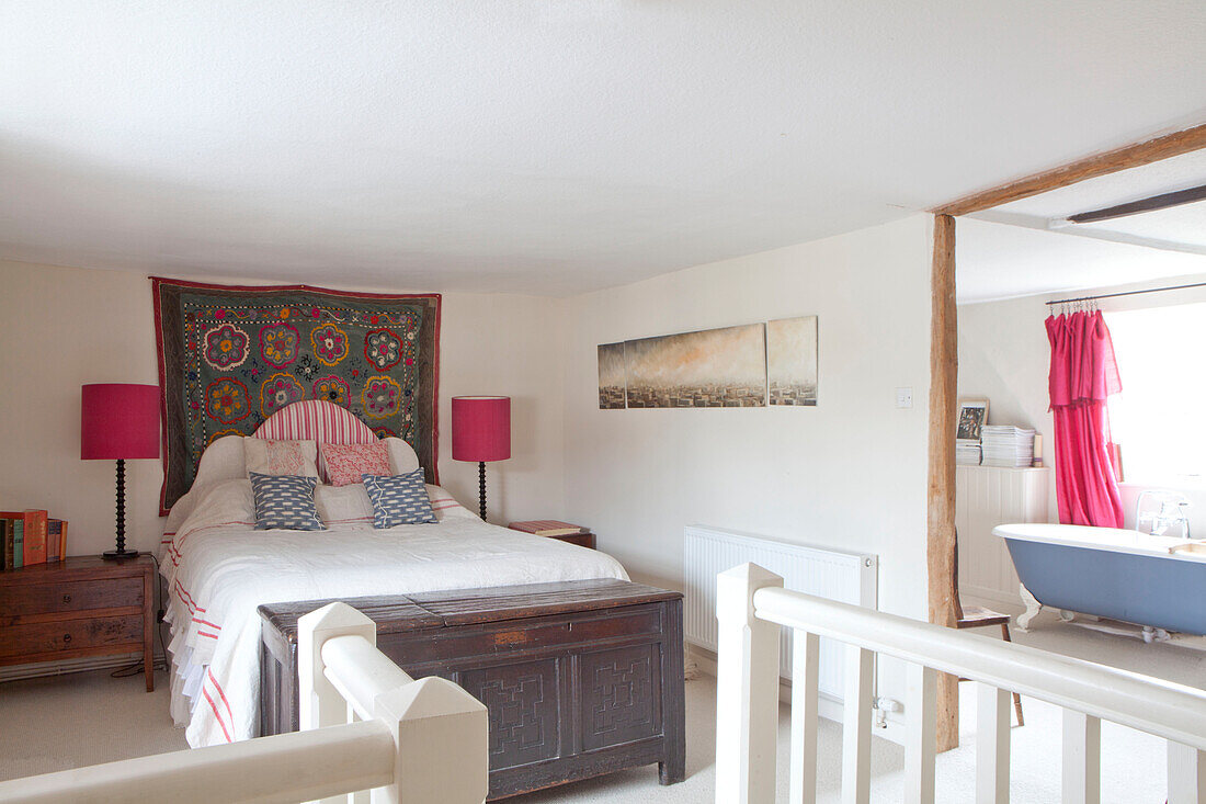 Knallrosa Lampenschirme und Wandbehang über dem Bett mit eigenem Bad in einem Haus in Großbritannien