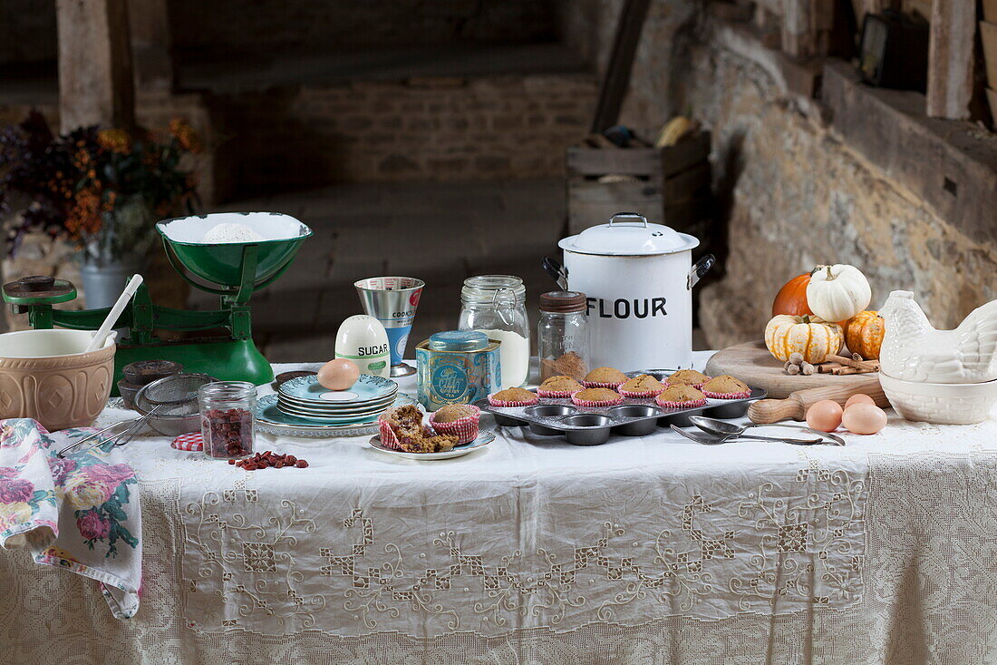 Baking ingredients on white tablecloth in rustic barn interior, United Kingdom