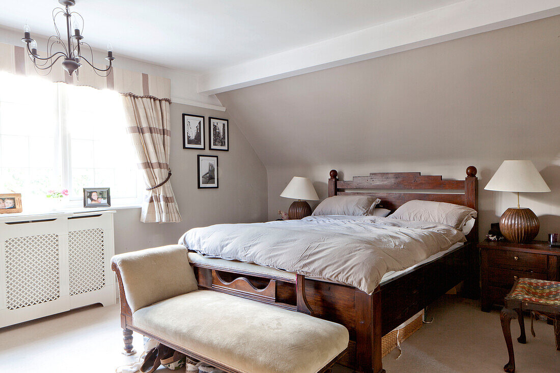 Antikes Holzbett und Chaiselongue im Schlafzimmer eines Hauses in Surrey England UK