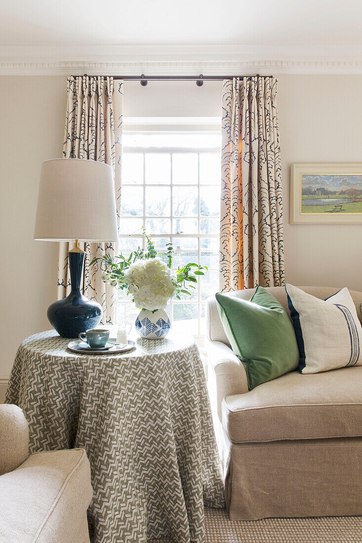 Lamp on circular table with geometric design cloth in window of London home UK