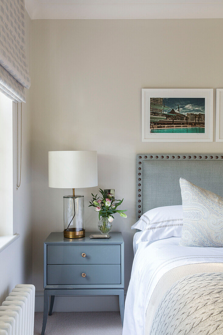 Gerahmte Drucke über einem Doppelbett mit hellblauem Nachttisch in einem Londoner Haus UK