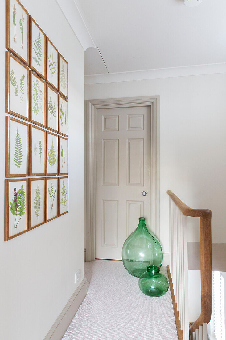 Gerahmte Blätter und grüne Glasvasen auf dem Treppenabsatz in einem Londoner Haus UK