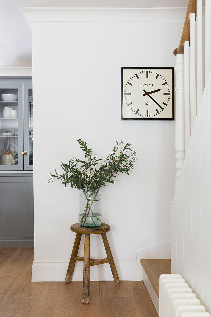 Moderne Uhr und Blätter in einer Vase auf einem Hocker in einem Londoner Haus UK