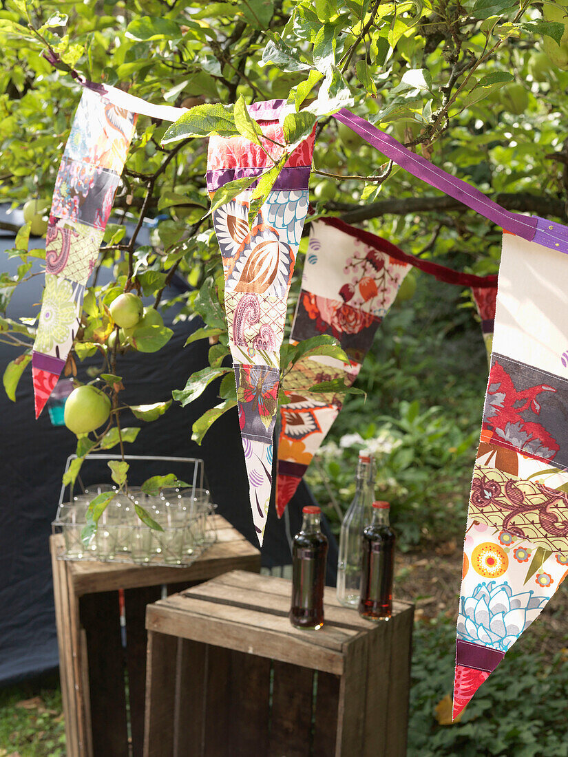 Bunting with bottles and glass carrier on crates with apple tree London England UK