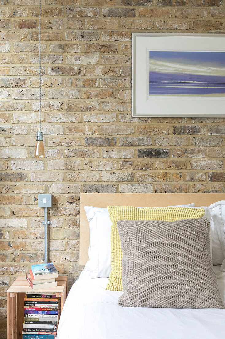 Artwork on exposed brick wall in bedroom of converted London courthouse UK