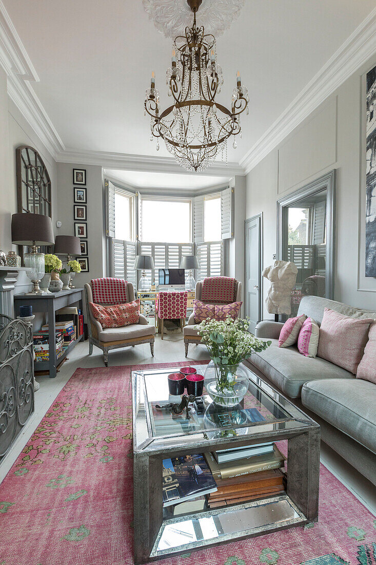 PInk hues and artwork with silver glass topped coffee table in living room of Victorian terrace Wandsworth London Uk