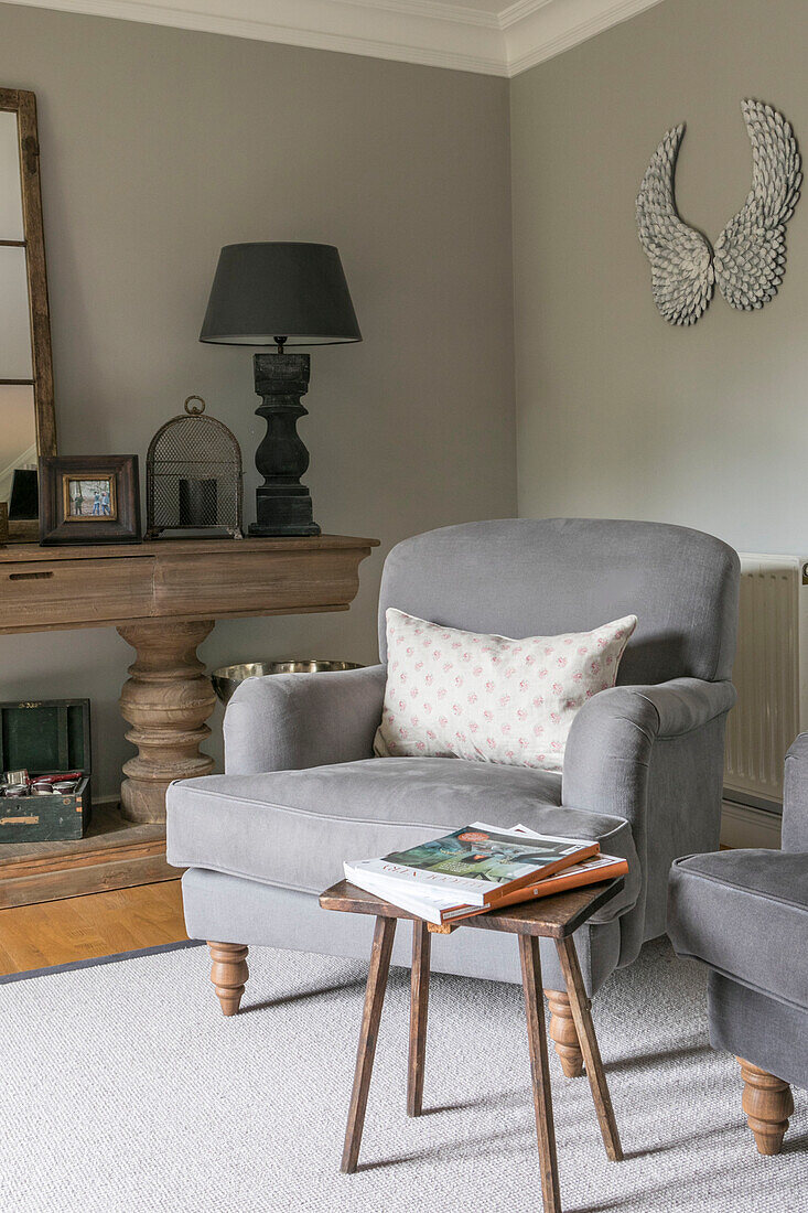 Light grey armchair with lamps on wooden console in Guildford townhouse Surrey UK